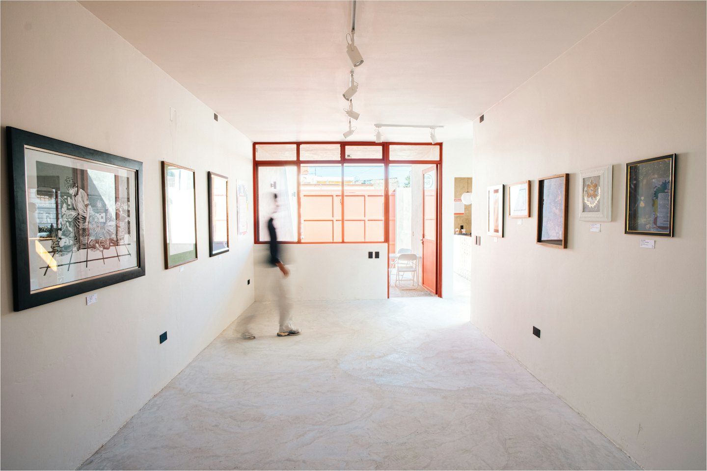 Person spaziert durch eine moderne Kunstgalerie mit gerahmten Kunstwerken.