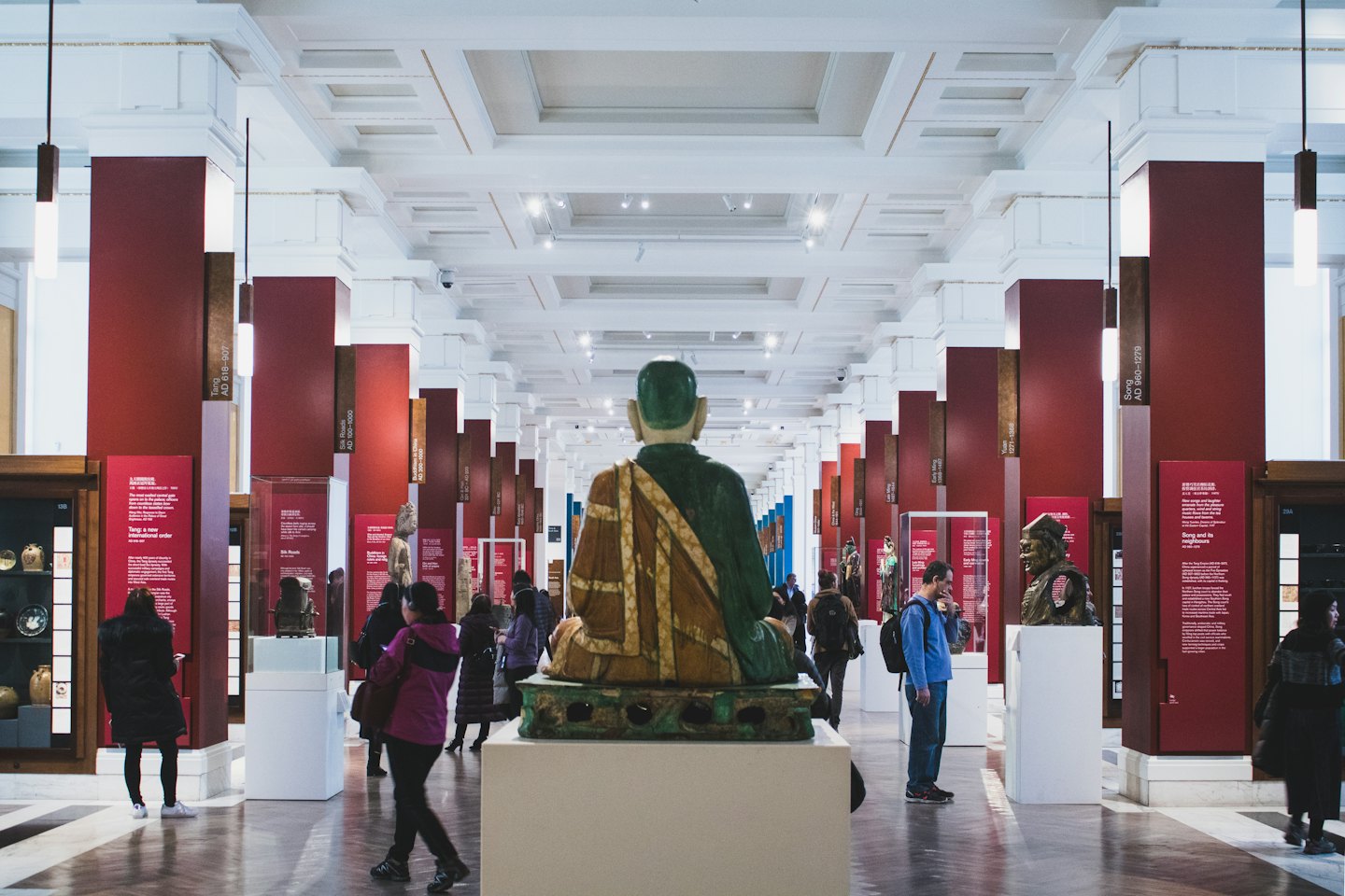 Menschen betrachten Exponate in einer großen Museumshalle mit einer großen Statue.